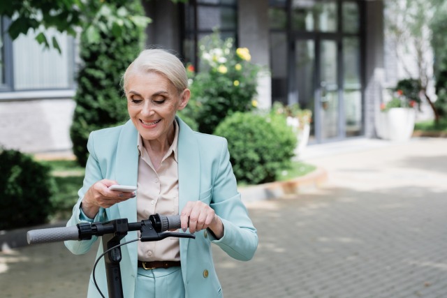 E-Scooter Frau bedient Handy