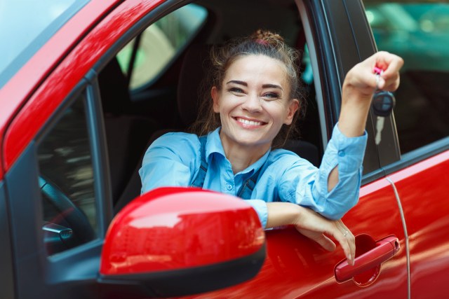 Frau im Autofenster mit Schlüssel in der Hand